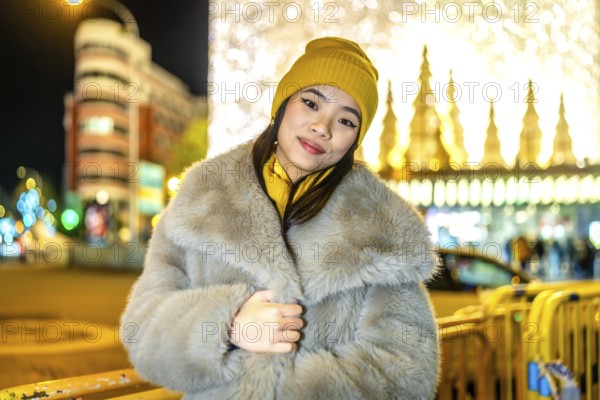 Fashionable young woman wearing winter clothes enjoying christmas night lights in the city