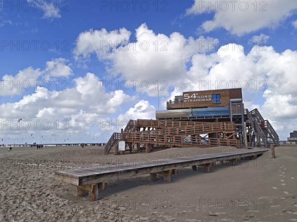 Pfahlbau Strandbar 54° Nord, California kitesurfing Masters 2025, kitesurfing, sport, pleasure, spectators, North Sea beach, blue sky, white clouds, summer, sun, sand, beach chairs, on the edge of the UNESCO World Heritage Site, Ording, Sankt Peter-Ording, Schleswig-Holstein, Germany