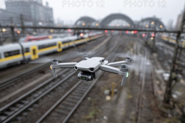 Ein Fernpilot steuert sein Quadrocopter, Drohne illegal über Bahnhofsgelände, Bahngelände, Bahnschienen, Symbolbild für illegaler Drohnenbetrieb über Bahnanlagen, kritische Infrastruktur, Kontrollierter Luftraum, Flugverbot, Betriebsverbot, gefährlicher Eingriff in den Bahnverkehr, AI generiert, AI generated