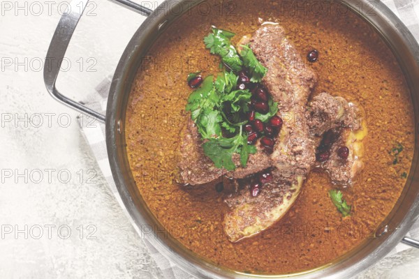 Fesenjan, an Iranian dish, stewed chicken, in a nut-pomegranate sauce, in a saucepan, light background, homemade, no people