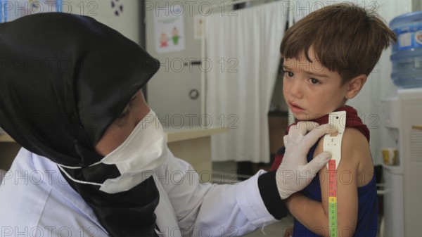 A doctor examines children's malnutrition inside a refugee camp. Malnutrition was measured using a mid-upper arm circumference belt. Aleppo, Syria October 29, 2022, Aleppo, Syria