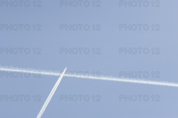 Jet passenger aircraft with a vapour trail or contrail flying in a blue sky, England, United Kingdom