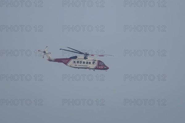 Sikorsky S-92A helicopter of the UK HM Coastguard flying in a blue sky, England, United Kingdom