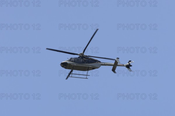 Bell 407GXP jet ranger helicopter flying in a blue sky, England, United Kingdom