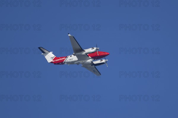 Beech King Air 350 light aircraft of the UK HM Coastguard flying in a blue sky, England, United Kingdom