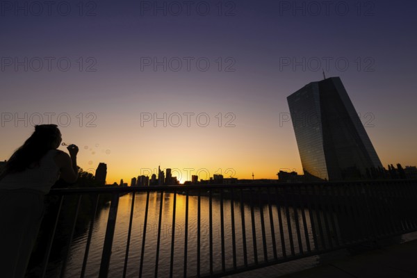 The sun sets behind the European Central Bank (ECB) and the Frankfurt banking skyline, Frankfurt am Main, Hesse, Germany