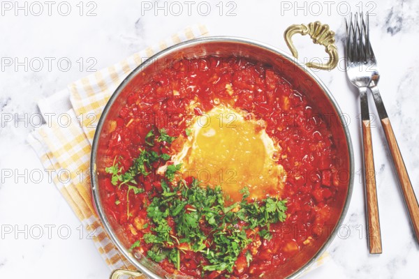 Traditional Turkish dish, scrambled eggs with tomatoes, Menemen, with herbs, in a frying pan, close-up, no people