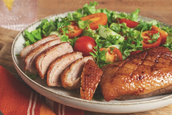 Delicious grilled duck breast served with fresh garden salad and cherry tomatoes at a rustic dining table