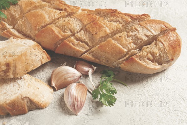 Garlic bread, baguette with garlic butter and herbs, on a light table, top view