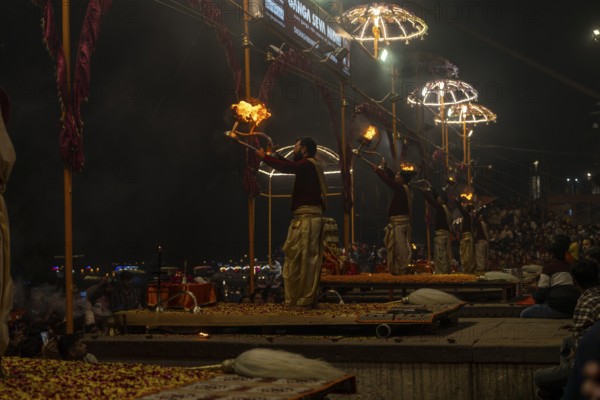 Hindu priest performing the Aarti ritual, holding a burning oil lamp, at the Ganges, Bangali Tola, Varanasi, Uttar Pradesh, India