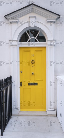 Bright yellow front door with neoclassical triangular pediment, Palladian-style entrance, white façade, Kensington, London, England, United Kingdom