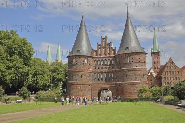 Historic Holsten Gate and pedestrians, tourists, St. Mary's Church, Lübeck St. Peter's Church Tower, Brick Gothic, brick buildings, towers, city gate, landmark, Holsten Gate Square, Old Town, Lübeck, Schleswig-Holstein, Germany