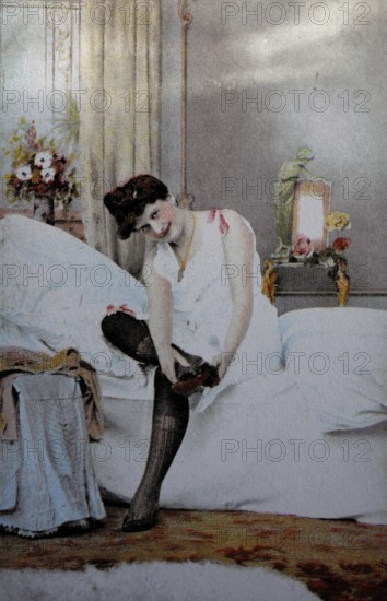 Female nude from around 1899, erotic postcard, playgirl, woman sitting on the bed and putting on stockings, personal morning moments in the bedroom, coloured, reproduction from a photo around the turn of the century, historical, digitally restored reproduction of an old original, exact date unknown