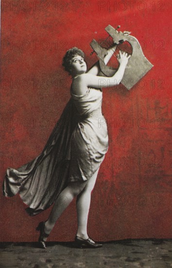 Female nude from around 1899, erotic postcard, playgirl, woman posing with an oversized harp in front of a bright red background, coloured, reproduction of a photo from around the turn of the century, historical, digitally restored reproduction of an old original, exact date unknown