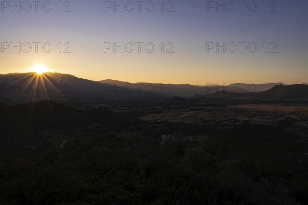 The sun sets behind the mountains on the Mediterranean island of Sardinia, Monte Nai, Costa Rei, Sardinia, Italy