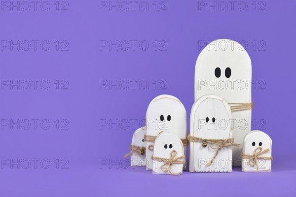 Cute wooden white Halloween ghost ornaments on purple background