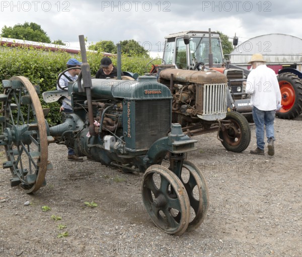 People viewing vintage Fordson tractors on display at auction, UK