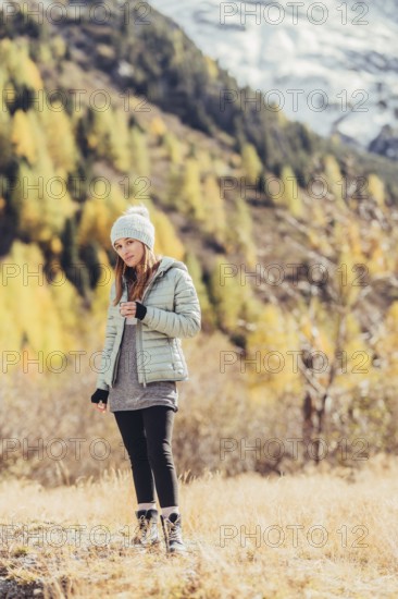 Woman in winter clothes in autumn Engadine with golden trees in Switzerland