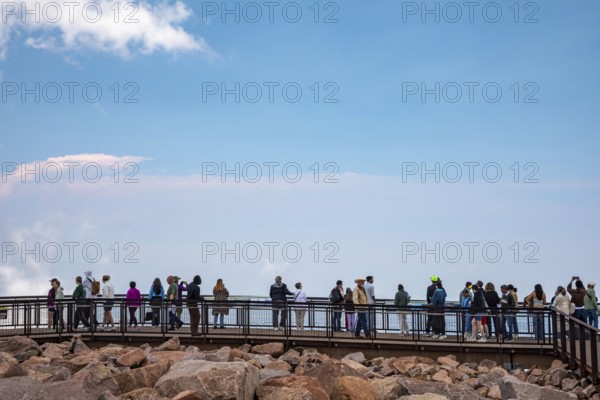 Colorado Springs, Colorado - Tourists line a viewing plantform at the summit of Pikes Peak, a 14, 115' mountain in Colorado's front range. Thousands of tourists visit, most by driving a steep road to the summit, or riding on a cog railway