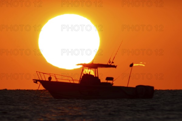 The sun rises behind a boat on the Costa Rei, a coastal stretch of the Italian Mediterranean island of Sardinia, Monte Nai, Costa Rei, Sardinia, Italy