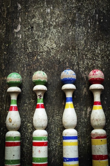 Vibrant wooden bowling pins stand aligned against a weathered surface, inviting players to enjoy a fun outdoor game with friends in a lively atmosphere