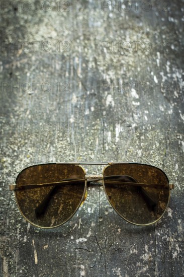 Vintage sunglasses rest on a weathered wooden surface, basking in gentle natural light. The scene evokes a sense of nostalgia and timeless style, inviting viewers to appreciate simple elegance
