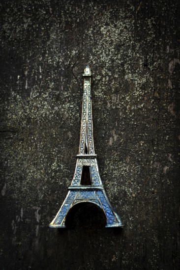 Vibrant blue Eiffel Tower keychain highlights detailed craftsmanship as it stands out against a textured dark surface, creating a striking visual contrast that captures attention