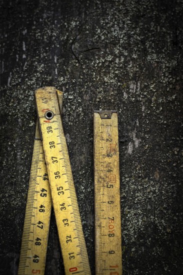Two antique wooden rulers rest on a rough, dark surface, showcasing their intricate details and nostalgic wear, illuminated by scattered light reflections