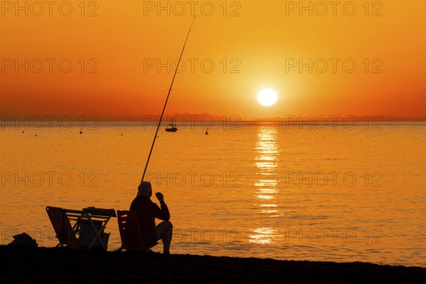 A man fishing shortly after sunrise on the Costa Rei, a stretch of coastline on the Italian island of Sardinia, in the Mediterranean Sea, Monte Nai, Costa Rei, Sardinia, Italy