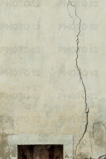 A cracked wall surface shows the passage of time with visible wear. The texture highlights light and shadow play, indicating an urban setting. Details unveil stories of neglect