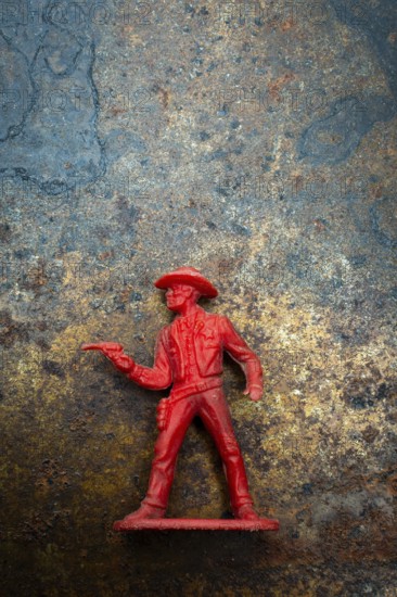 A red cowboy figure is positioned confidently with a raised finger, set against an intriguing textured background that enhances its vintage charm