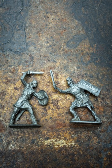 Two plast miniature figures depict a warrior with a shield and sword facing off against a roman soldier wielding a sword and shield