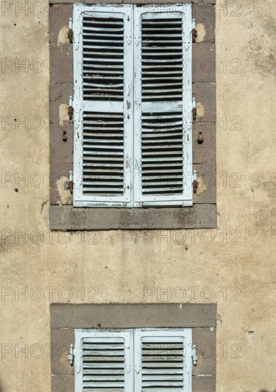 Two sets of vintage blue shutters add charm to a weathered wall, showcasing the beauty of rustic architecture and evoking a sense of history and character. France