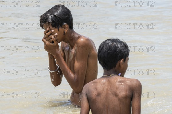Children bathe in the Brahmaputra River to seek relief from the intense summer heat in Guwahati, India, on June 26, 2025
