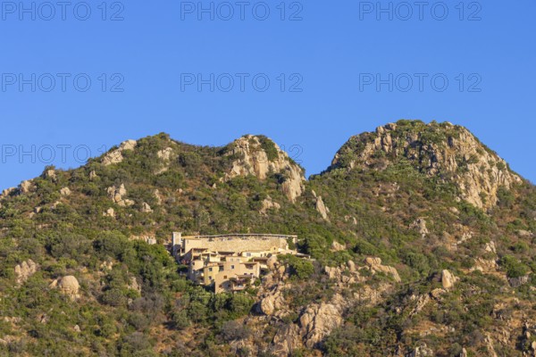 Small houses built into the steep, rocky slope characterise the landscape on the Costa Rei, a stretch of coastline on the Italian Mediterranean island of Sardinia, Monte Nai, Costa Rei, Sardinia, Italy