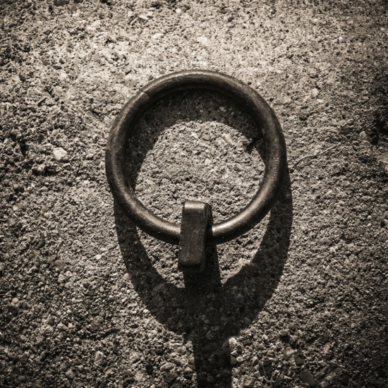 Mooring rings made of iron are embedded in the dockside, showcasing a rugged texture under soft twilight light. Shadows stretch across the concrete, enhancing the industrial aesthetic
