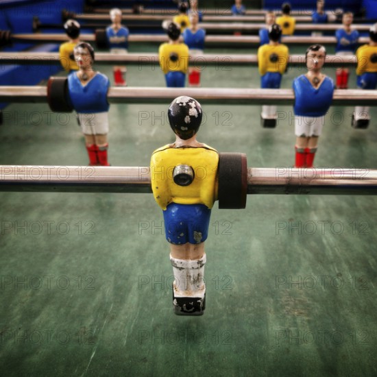 In a vibrant recreation space, a vintage table football game features colorful player figurines ready to engage in a competitive match. The atmosphere is energetic and nostalgic