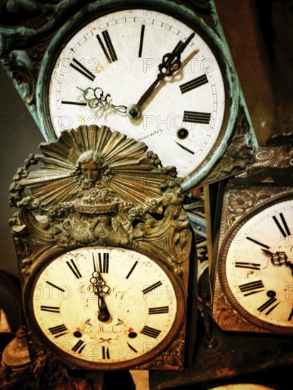 A collection of vintage clocks showcasing ornate craftsmanship and classic styling. Each clock features Roman numerals and unique decorative elements, highlighting their historical significance