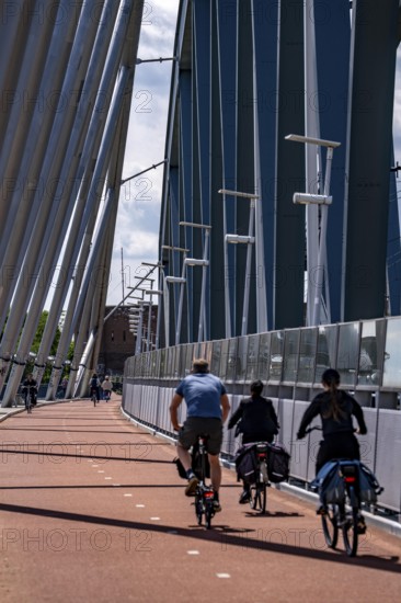 Cycle and pedestrian bridge Snelbinder Brug, over the river Waal near Nijmegen, was added to the existing railway bridge, fast cycle path connection from the city centre of Nijmegen and the new housing estates in the Waalsprong district, Netherlands