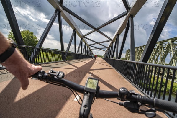 Ride over the De Massover cycle path bridge, over the Meuse south of Nijmegen, near Cuijk, part of the MaasWaalpad long-distance cycle path, 12 km between Nijmegen and Cuijk, built in 2021, for 15 million euros, Meuse river crossing for cyclists and pedestrians, part of a cycle path network, used by many commuters, next to a railway bridge, Netherlands
