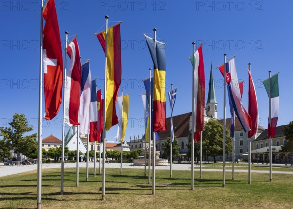 National flags at Kapellplatz with the collegiate parish church of St Philip and St James, place of pilgrimage, Altötting, Upper Bavaria, Bavaria, Germany