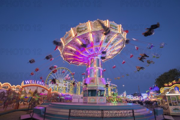 Brightly illuminated carousel at a night fair, chain carousel, spring festival, Cannstatter Wellenflug, illuminated, blue hour, Cannstatter Wasen, Bad Cannstatt, Stuttgart, Baden-Württemberg, Germany