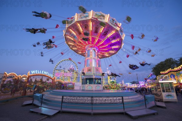 Luminous carousel turns on a colourful funfair, chain carousel, spring festival, Cannstatter Wellenflug, illuminated, blue hour, Cannstatter Wasen, Bad Cannstatt, Stuttgart, Baden-Württemberg, Germany