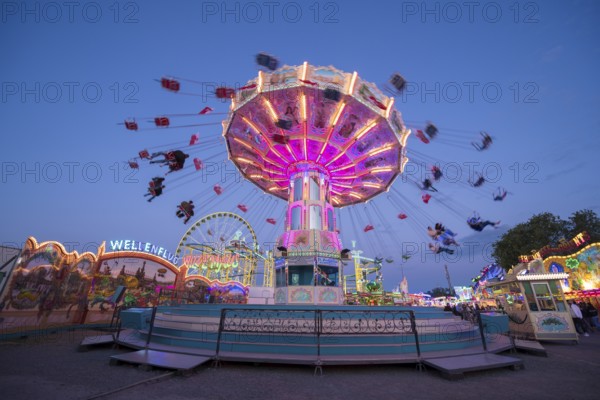 Colourful carousel in motion at a night fair, chain carousel, spring festival, Cannstatter Wellenflug, illuminated, blue hour, Cannstatter Wasen, Bad Cannstatt, Stuttgart, Baden-Württemberg, Germany