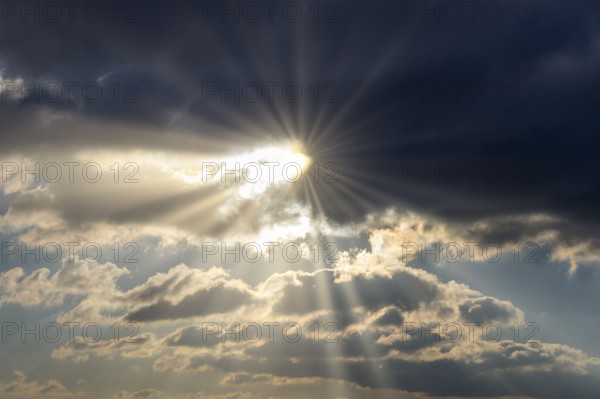 Dramatic rays of sunshine break through dark clouds in the sky, Baden-Württemberg, Germany