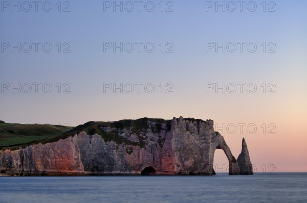 Rock arch Falaise or Porte d'Aval and rock needle Aiguille, illuminated, illuminated, Étretat, sea, steep coast, cliffs, chalk cliffs, alabaster coast, La Côte d'Albâtre, sunset, evening mood, atmospheric, Normandy, Seine-Maritime, France