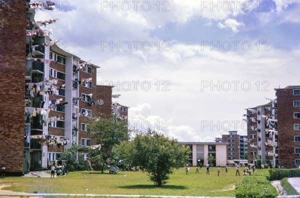 Children playing on grass area of residential area with blocks of flats, Singapore, southeast Asia c 1963