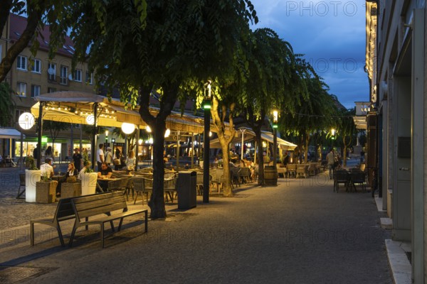 Night shot of the Peace Square in the historic centre of Trencín, visitors sitting in a café, Capital of Culture 2026, Trencín, Slovakia