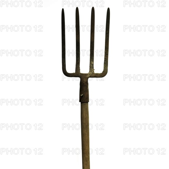 A metal fork with four sharp prongs stands upright against a plain white background. The wooden handle is aged and shows signs of wear, highlighting its use in agricultural tasks