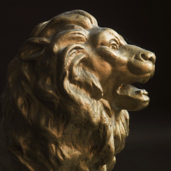 A lion head sculpture stands out with its detailed mane and expressive features. It captures the essence of strength and majesty with a golden hue under warm lighting